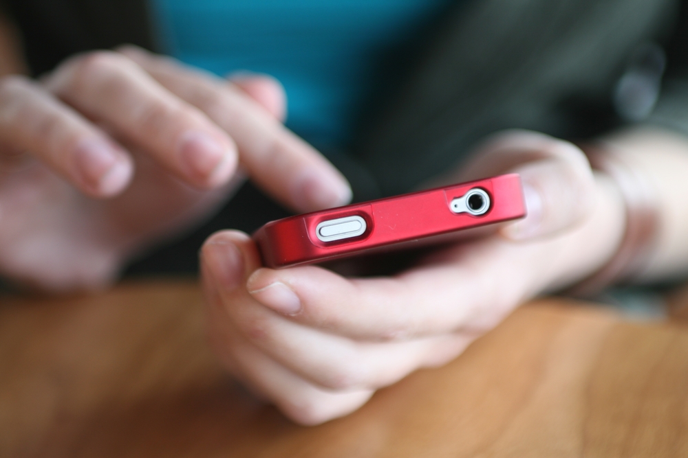 A person's hands holding a red smartphone